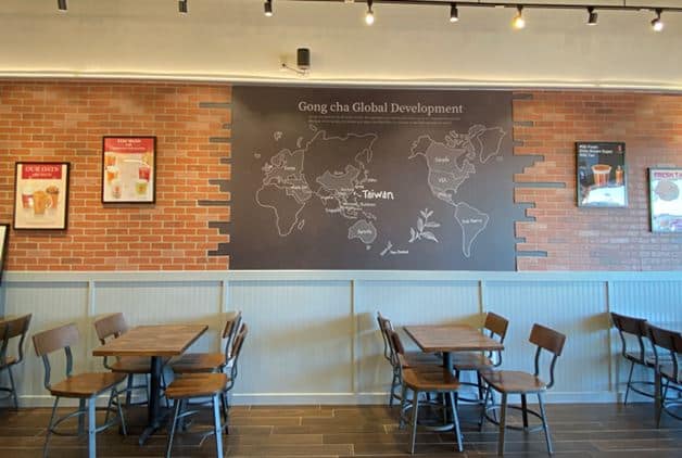Interior image of Gong cha bubble tea store with chalkboard map and wood tables
