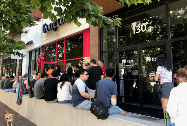 Image of exterior Gong cha store with a line of guests sitting on a concrete wall