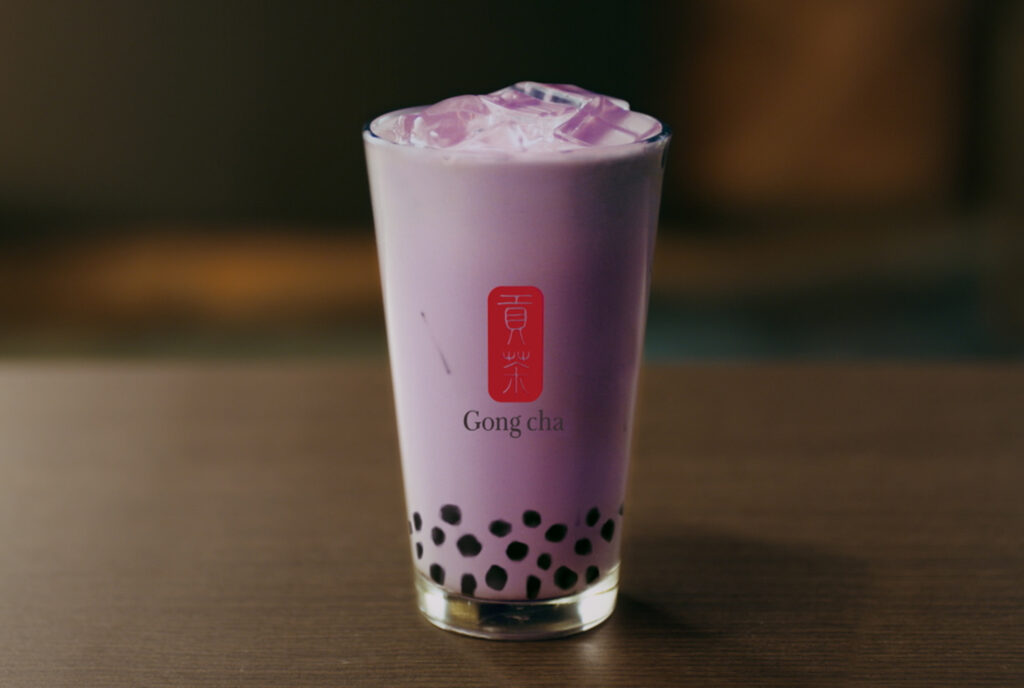 Image of a purple bubble tea in a Gong cha glass on a brown table