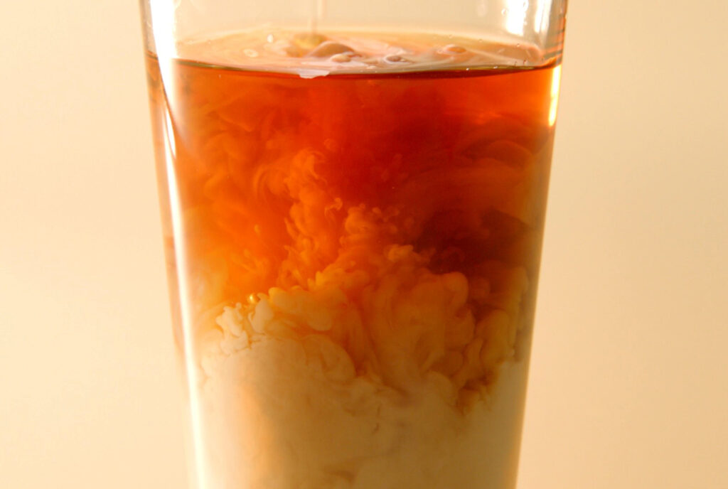 Image of milk and red tea in a glass on an orange background