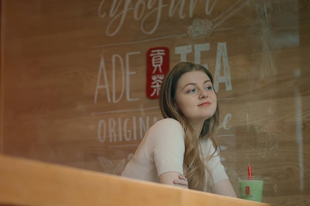 girl looking out the window of a Gong Cha business